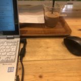 STORY CAFEのテーブルの上。パソコンとトレイ、PC用マウスが写っている。トレイには飲みかけののみもの。